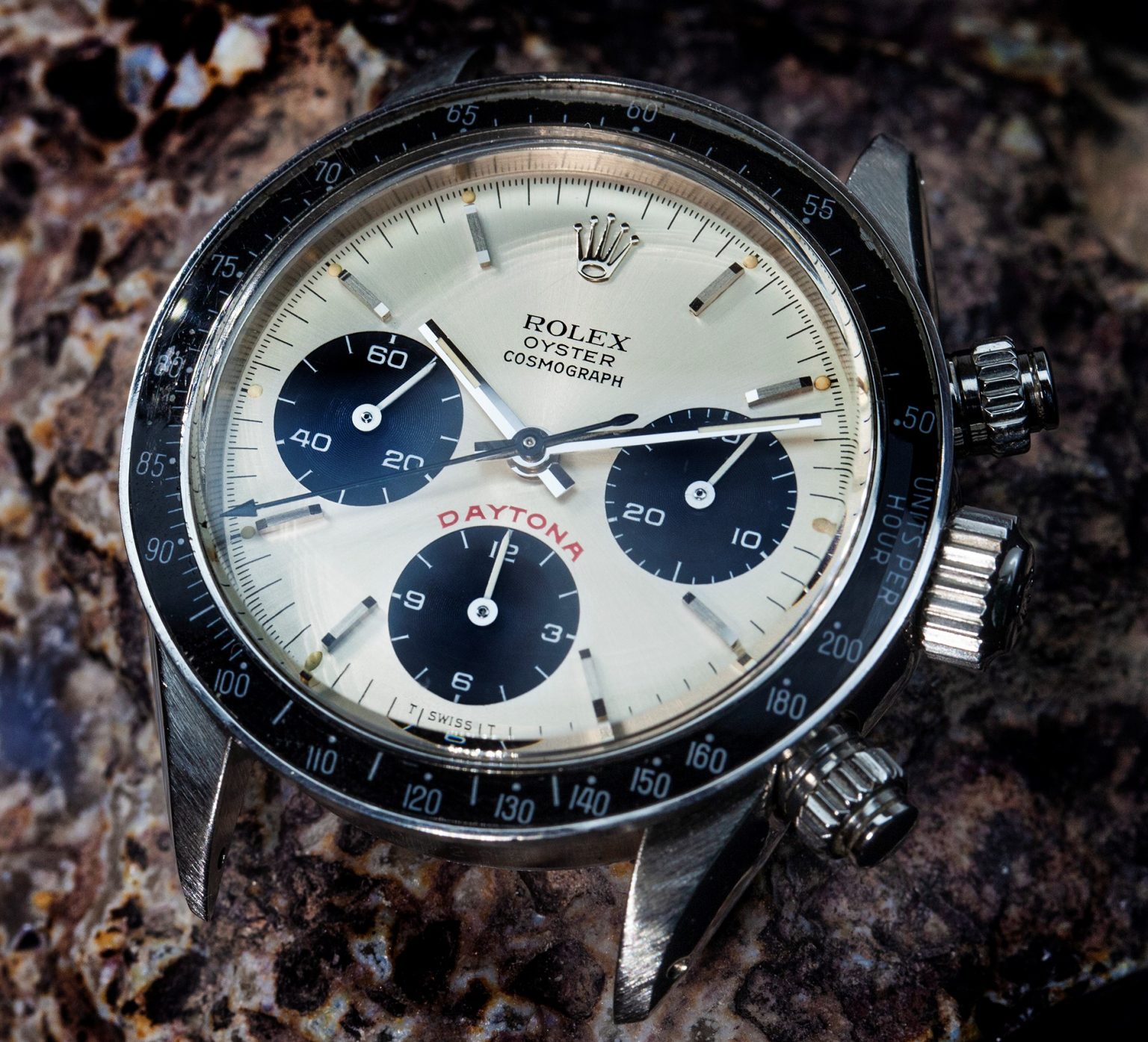 Vintage chronograph watch with black bezel resting on dark stone
